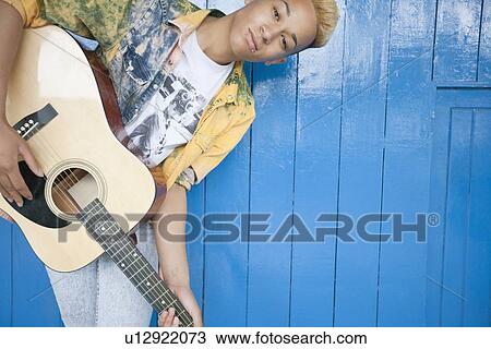 Portrait of a teenage boy playing guitar against wood paneled wall View Large Photo Image Stock Image - Portrait of a teenage boy playing guitar against wood paneled wall. Fotosearch
