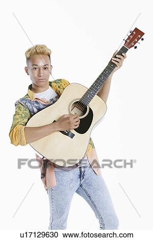 Portrait of a teenage boy playing guitar over gray background View Large Photo Image Stock Image - Portrait of a teenage boy playing guitar over gray background. Fotosearch