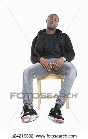 Portrait of a trendy African American man sitting on chair over gray background View Large Photo Image Stock Image - Portrait of a trendy African American man sitting on chair over gray background. Fotosearch