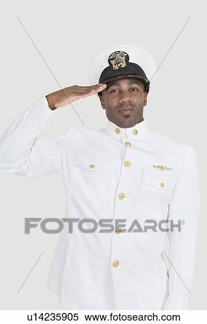 Stock Photography - Portrait of a young African American US Navy officer saluting over gray background. Fotosearch