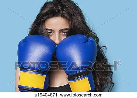 Portrait of a young female boxer with fists up against blue background View Large Photo Image Stock Image - Portrait of a young female boxer with fists up against blue background. Fotosearch