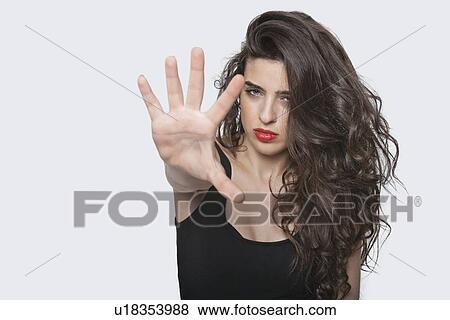 Portrait of a young female gesturing stop sign over gray background View Large Photo Image Stock Photo - Portrait of a young female gesturing stop sign over gray background. Fotosearch