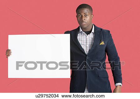 Picture - Portrait of a young smart man wearing coat with blank cardboard over pink background. Fotosearch