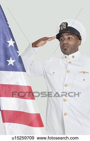 Portrait of a young US Navy officer saluting American flag over gray background View Large Photo Image Stock Photo - Portrait of a young US Navy officer saluting American flag over gray background. Fotosearch