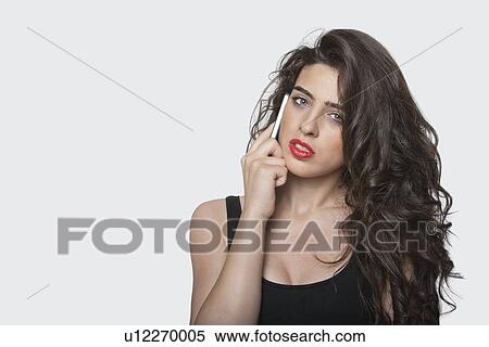 Portrait of a young woman using cell phone over gray background View Large Photo Image Stock Photography - Portrait of a young woman using cell phone over gray background. Fotosearch