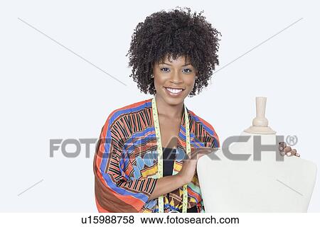 Stock Photo - Portrait of African American female fashion designer with tailor's dummy over gray background. Fotosearch