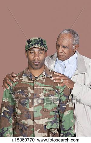 Stock Image - Portrait of African American male US Marine Corps soldier with father over brown background. Fotosearch