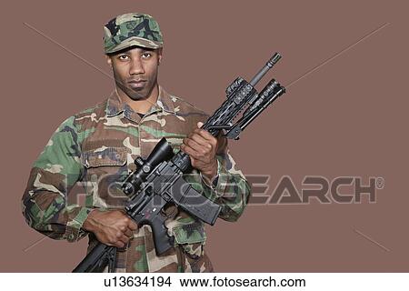 Picture - Portrait of African American US Marine Corps soldier holding M4 assault rifle over brown background. Fotosearch
