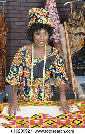 Stock Photo - Portrait of an African American female fashion designer with sewing pattern and cloth. Fotosearch