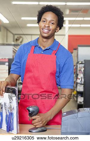 Stock Photography - Portrait of an African American male store clerk standing at checkout counter. Fotosearch