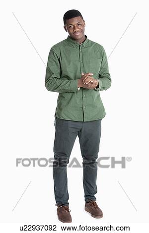 Stock Image - Portrait of an African American man standing with hands clasped over gray background. Fotosearch