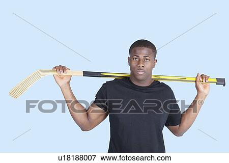 Portrait of an African American man holding hockey stick over blue background View Large Photo Image Stock Photo - Portrait of an African American man holding hockey stick over blue background. Fotosearch