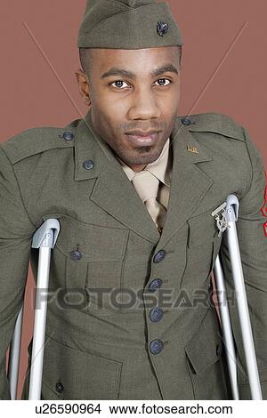 Portrait of an African American US military officer with crutches over brown background View Large Photo Image Picture - Portrait of an African American US military officer with crutches over brown background. Fotosearch