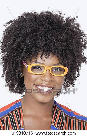 Stock Photograph - Portrait of an African American woman wearing glasses over gray background. Fotosearch