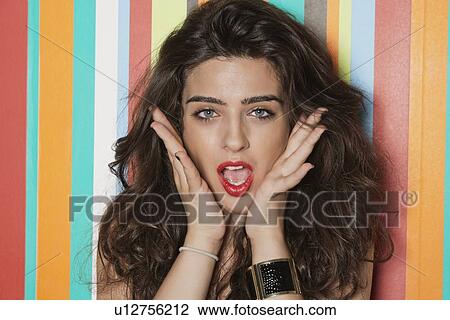 Portrait of an amazed young woman over colorful striped background View Large Photo Image Stock Image - Portrait of an amazed young woman over colorful striped background. Fotosearch