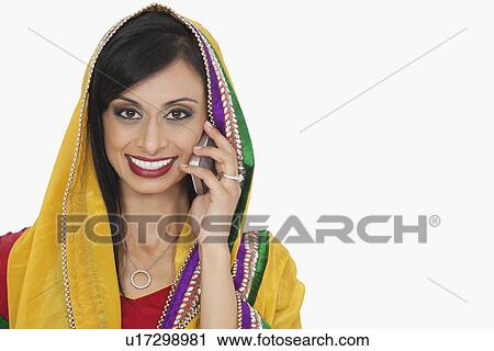 Portrait of an attractive Indian woman in traditional wear answering phone call over white background View Large Photo Image Stock Image - Portrait of an attractive Indian woman in traditional wear answering phone call over white background. Fotosearch