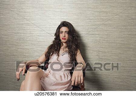 Portrait of an attractive young woman sitting on chair over textured background View Large Photo Image Stock Image - Portrait of an attractive young woman sitting on chair over textured background. Fotosearch