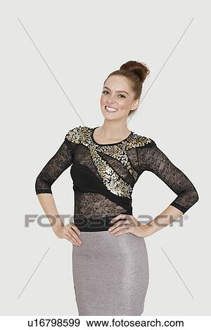 Portrait of an attractive young woman standing hands on hips over colored background View Large Photo Image Stock Photo - Portrait of an attractive young woman standing hands on hips over colored background. Fotosearch
