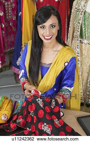 Portrait of an Indian female dressmaker matching thread color with the cloth View Large Photo Image Stock Image - Portrait of an Indian female dressmaker matching thread color with the cloth. Fotosearch