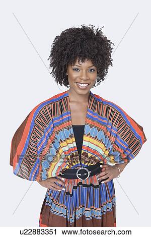 Stock Image - Portrait of beautiful African American woman in traditional wear standing over gray background. Fotosearch