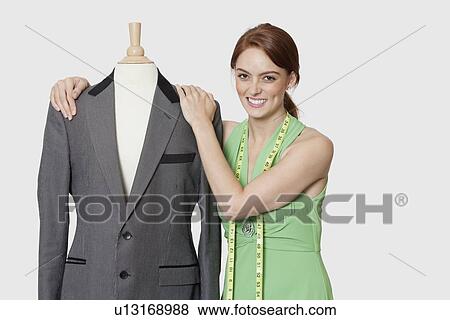 Portrait of beautiful female dressmaker standing with tailor's dummy over gray background View Large Photo Image Stock Photo - Portrait of beautiful female dressmaker standing with tailor's dummy over gray background. Fotosearch