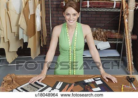Portrait of beautiful female fashion designer standing at table with layouts View Large Photo Image Picture - Portrait of beautiful female fashion designer standing at table with layouts. Fotosearch
