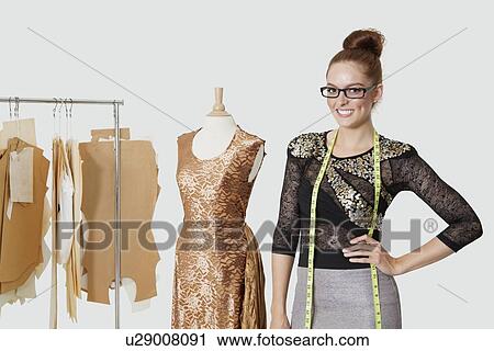 Portrait of beautiful female fashion designer standing with hand on hip over gray background View Large Photo Image Stock Image - Portrait of beautiful female fashion designer standing with hand on hip over gray background. Fotosearch