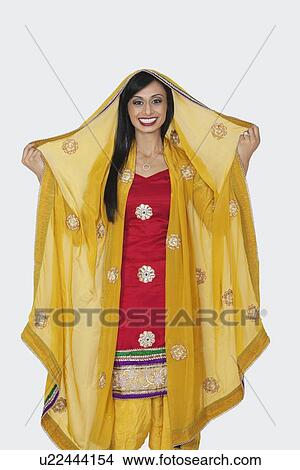 Portrait of beautiful Indian woman in salwar kameez standing over gray background View Large Photo Image Picture - Portrait of beautiful Indian woman in salwar kameez standing over gray background. Fotosearch