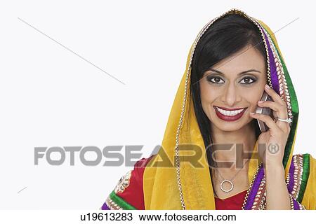 Portrait of beautiful Indian woman in traditional wear answering phone call over white background View Large Photo Image Stock Image - Portrait of beautiful Indian woman in traditional wear answering phone call over white background. Fotosearch