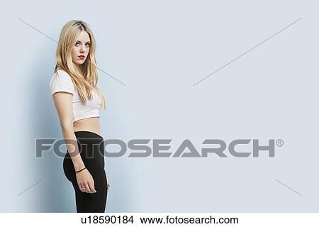 Picture - Portrait of beautiful young blond woman with red lips standing against blue background. Fotosearch
