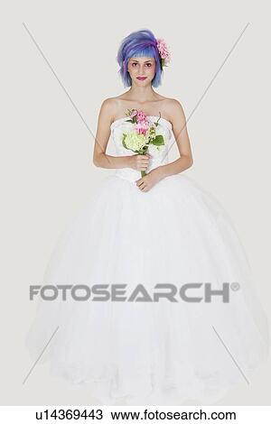 Stock Image - Portrait of beautiful young woman in wedding outfit with dyed hair against gray background. Fotosearch