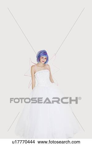 Picture - Portrait of beautiful young woman dressed as angel with dyed hair against gray background. Fotosearch