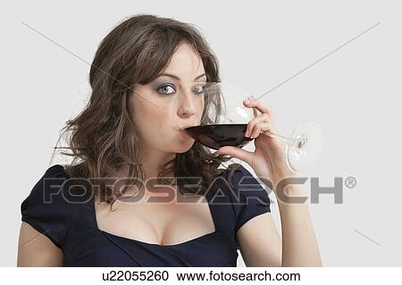 Portrait of beautiful young woman drinking wine against gray background View Large Photo Image Stock Image - Portrait of beautiful young woman drinking wine against gray background. Fotosearch