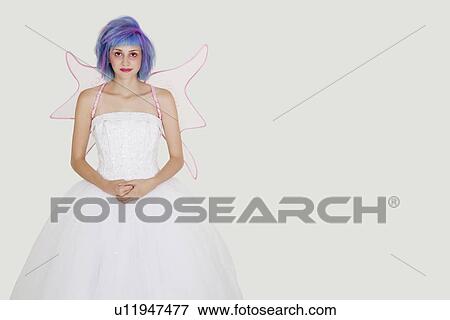 Stock Photo - Portrait of beautiful young woman dressed as angel with dyed hair against gray background. Fotosearch