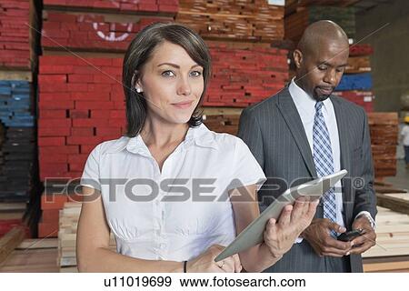 Portrait of businesswoman holding tablet PC while colleague using cell phone View Large Photo Image Stock Photo - Portrait of businesswoman holding tablet PC while colleague using cell phone. Fotosearch