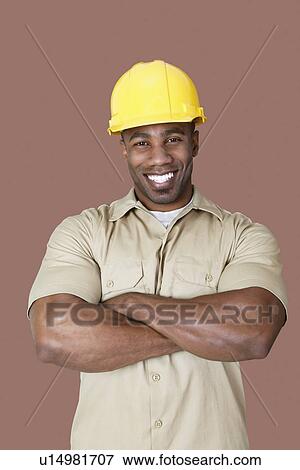 Stock Photo - Portrait of cheerful young African construction worker over brown background. Fotosearch