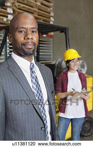 Portrait of confident African American male businessman with female worker standing in background View Large Photo Image Stock Image - Portrait of confident African American male businessman with female worker standing in background. Fotosearch
