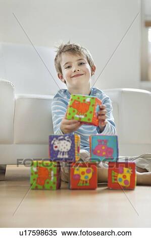Portrait of cute little boy stacking blocks while sitting on floor View Large Photo Image Stock Photography - Portrait of cute little boy stacking blocks while sitting on floor. Fotosearch