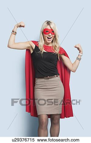 Portrait of excited young blond woman in superhero costume flexing arms over light blue background View Large Photo Image Stock Photography - Portrait of excited young blond woman in superhero costume flexing arms over light blue background. Fotosearch