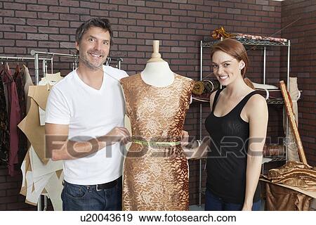 Stock Photo - Portrait of fashion designers working together on an outfit in design studio. Fotosearch