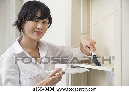 Picture - Portrait of female housekeeper cleaning shelf. Fotosearch