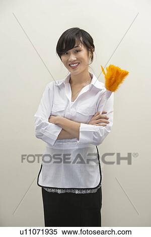 Portrait of female housekeeper holding feather duster against gray background View Large Photo Image Stock Photography - Portrait of female housekeeper holding feather duster against gray background. Fotosearch