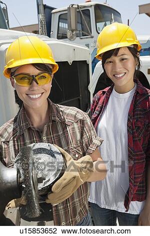Portrait of female industrial worker buffing a truck engine cylinder with coworker standing besides her View Large Photo Image Stock Image - Portrait of female industrial worker buffing a truck engine cylinder with coworker standing besides her. Fotosearch