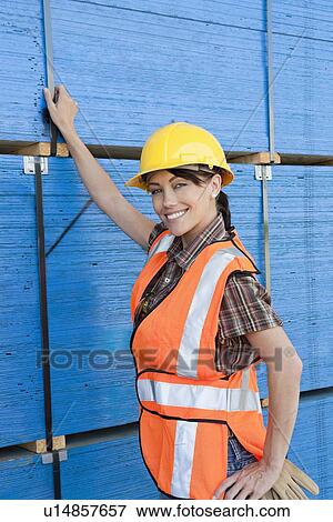 Portrait of female industrial worker standing by stacked wooden planks View Large Photo Image Stock Photo - Portrait of female industrial worker standing by stacked wooden planks. Fotosearch
