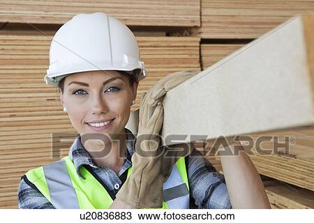 Portrait of female worker carrying wooden plank on shoulder View Large Photo Image Stock Image - Portrait of female worker carrying wooden plank on shoulder. Fotosearch