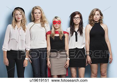 Stock Image - Portrait of five young women standing side by side against light blue background. Fotosearch