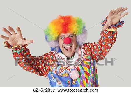 Portrait of funny clown with arms raised and mouth open against colored background View Large Photo Image Stock Photo - Portrait of funny clown with arms raised and mouth open against colored background. Fotosearch