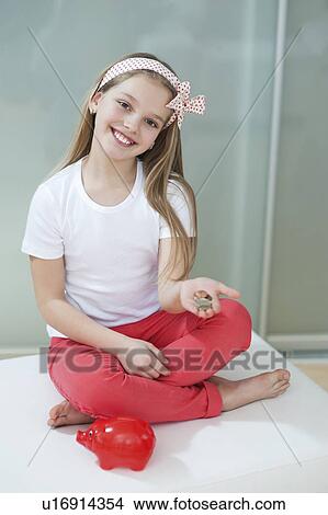 Portrait of girl with piggy bank and coins sitting in bed View Large Photo Image Picture - Portrait of girl with piggy bank and coins sitting in bed. Fotosearch