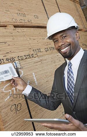 Portrait of happy African American male contractor using tablet PC while inspecting wooden planks View Large Photo Image Stock Image - Portrait of happy African American male contractor using tablet PC while inspecting wooden planks. Fotosearch