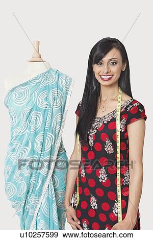 Portrait of happy Indian female fashion designer standing by dummy draped in a sari View Large Photo Image Stock Photo - Portrait of happy Indian female fashion designer standing by dummy draped in a sari. Fotosearch